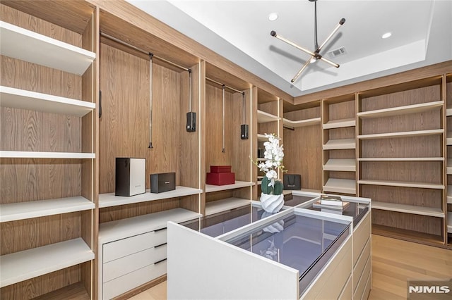 office space with a tray ceiling, visible vents, light wood-style flooring, and recessed lighting