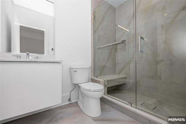 bathroom featuring toilet, a stall shower, baseboards, and vanity