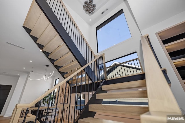 stairs featuring a towering ceiling, visible vents, and recessed lighting