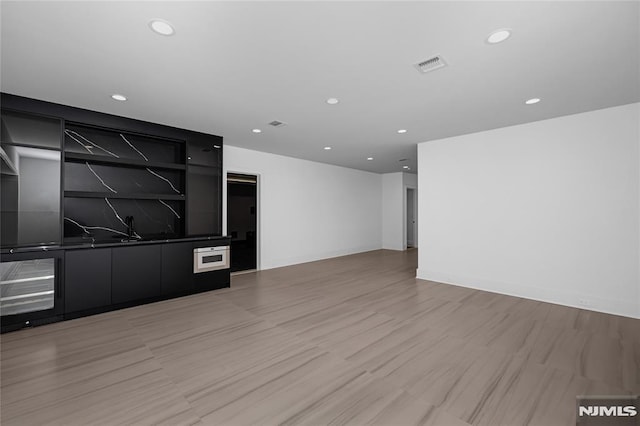 unfurnished living room with light wood-type flooring, visible vents, and recessed lighting