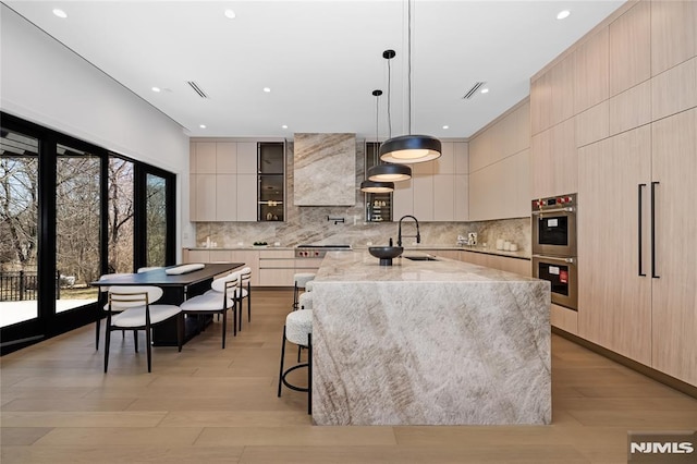 kitchen with light stone counters, a sink, appliances with stainless steel finishes, decorative backsplash, and modern cabinets