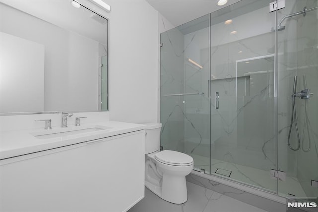 bathroom featuring toilet, marble finish floor, a marble finish shower, and vanity