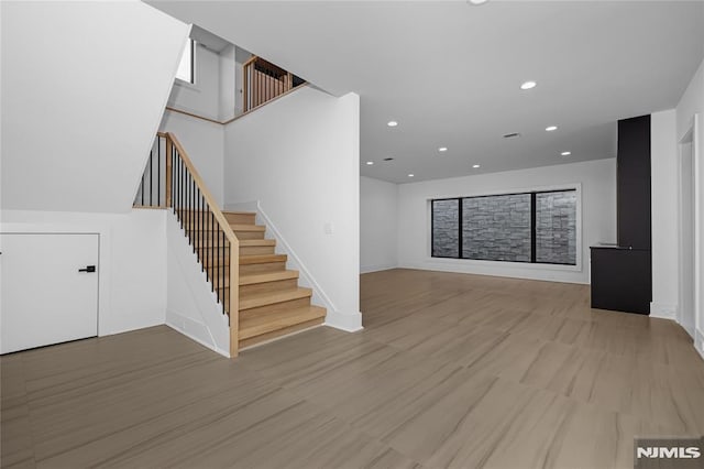 unfurnished living room featuring stairs, baseboards, wood finished floors, and recessed lighting