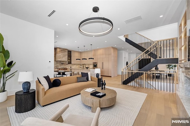 living area featuring stairs, recessed lighting, visible vents, and light wood-style floors