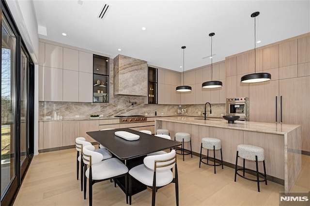 kitchen with a breakfast bar area, a sink, visible vents, a large island, and modern cabinets