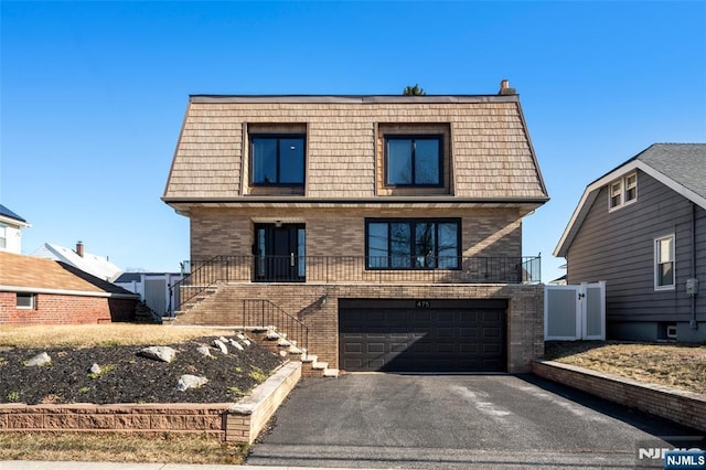 view of front of property with mansard roof, stairway, aphalt driveway, and brick siding