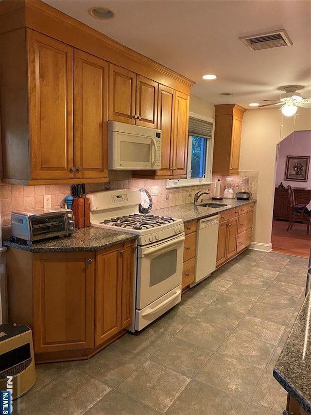 kitchen with white appliances, backsplash, a sink, ceiling fan, and brown cabinetry