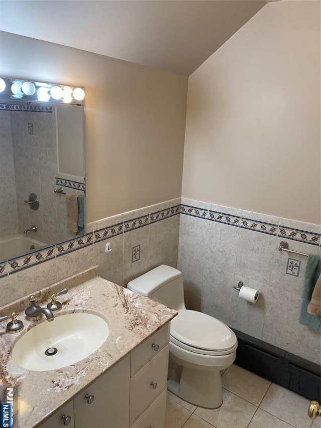 bathroom with tile walls, tile patterned floors, toilet, a wainscoted wall, and vanity