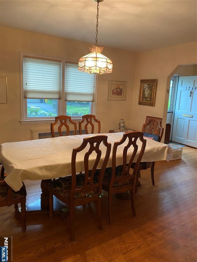 dining area with arched walkways and wood finished floors