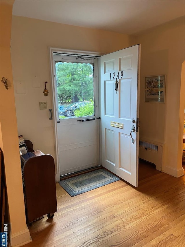 doorway with radiator and light wood-type flooring