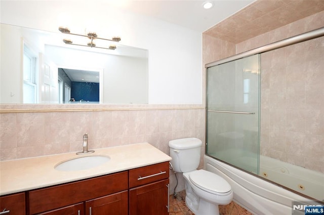 full bath with toilet, a combined bath / shower with jetted tub, tile walls, and vanity