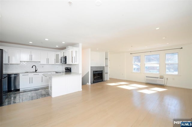 kitchen featuring black appliances, tasteful backsplash, a sink, and light wood-style floors