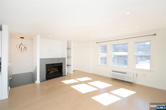 unfurnished living room featuring baseboards, wood finished floors, a wall mounted AC, a fireplace, and recessed lighting