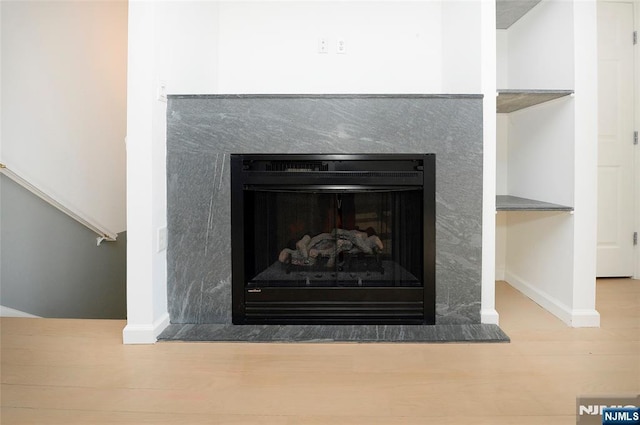 interior details featuring a fireplace, baseboards, and wood finished floors