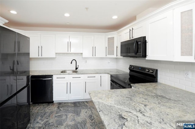 kitchen with black appliances, light stone counters, white cabinets, and a sink