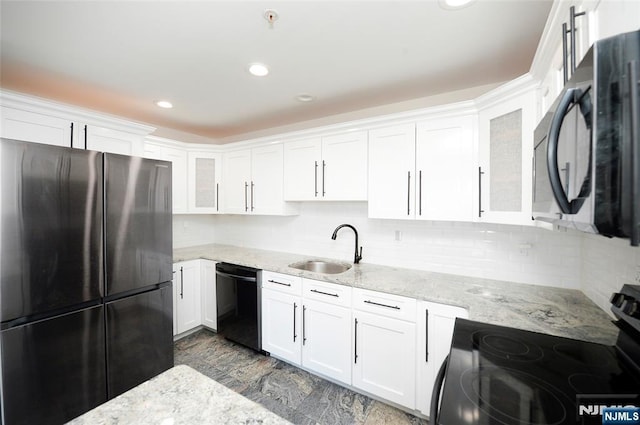 kitchen with glass insert cabinets, light stone countertops, black appliances, white cabinetry, and a sink