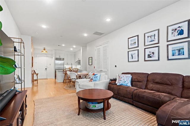 living area with light wood-type flooring, visible vents, and recessed lighting