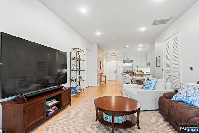 living area featuring light wood-type flooring, visible vents, and recessed lighting