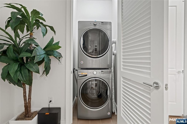 laundry room with stacked washer and dryer, tile patterned flooring, and laundry area