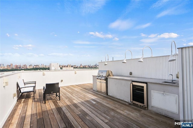 wooden terrace with beverage cooler, grilling area, exterior kitchen, a city view, and a sink