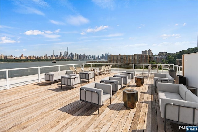 deck featuring an outdoor living space with a fire pit, a city view, and a water view