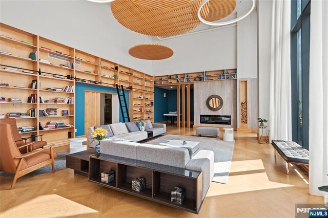 interior space with built in shelves, a glass covered fireplace, and a high ceiling