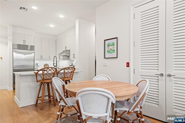 dining space featuring baseboards, light wood finished floors, visible vents, and recessed lighting