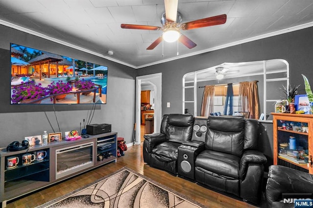 cinema room with ornamental molding, ceiling fan, and wood finished floors