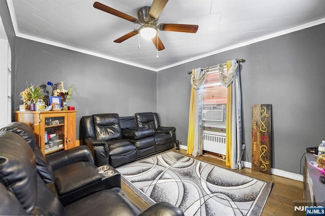 living area featuring cooling unit, wood finished floors, baseboards, radiator, and crown molding