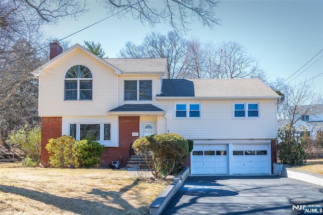 view of front facade featuring a garage, brick siding, driveway, and a chimney