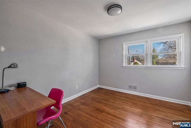 unfurnished office featuring visible vents, baseboards, and wood finished floors