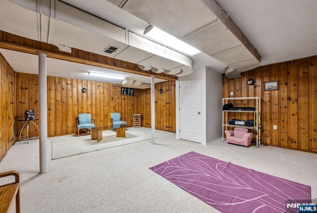 finished basement with wooden walls, visible vents, and carpet floors