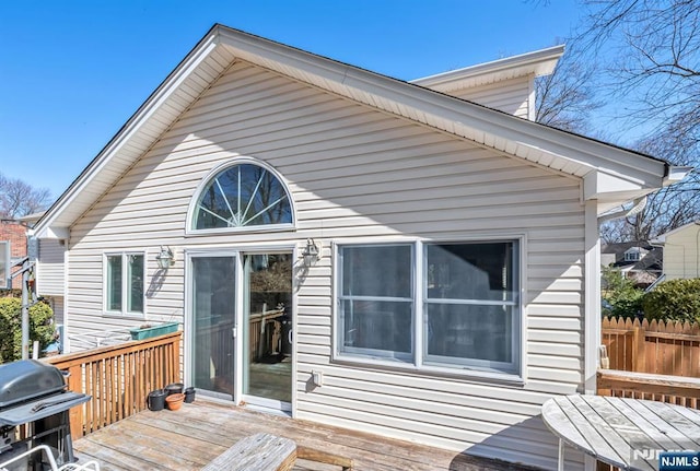 rear view of property with a wooden deck and fence