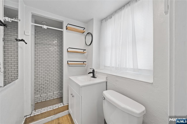 bathroom featuring wood finished floors, a stall shower, vanity, and toilet