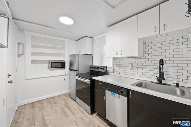 kitchen featuring stainless steel appliances, a sink, white cabinetry, light countertops, and light wood-type flooring