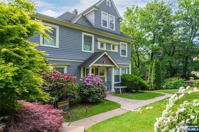 view of front of home featuring a chimney and a front lawn