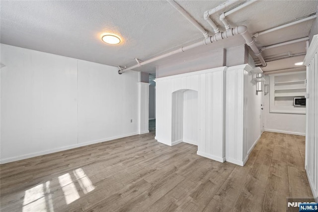 basement featuring a textured ceiling and wood finished floors