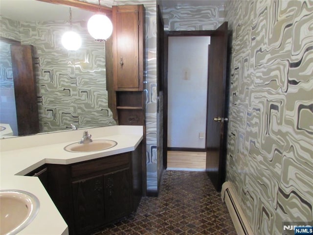 bathroom with baseboard heating, vanity, and wallpapered walls