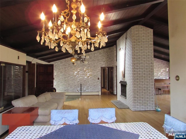 living area with lofted ceiling with beams, a fireplace, wood finished floors, and a notable chandelier