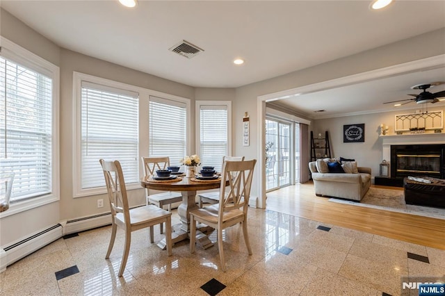 dining room with baseboards, visible vents, a glass covered fireplace, and recessed lighting