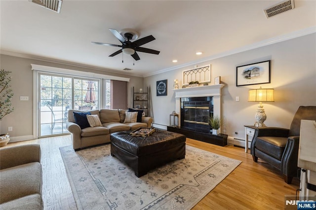 living room with ornamental molding, visible vents, and light wood-style floors