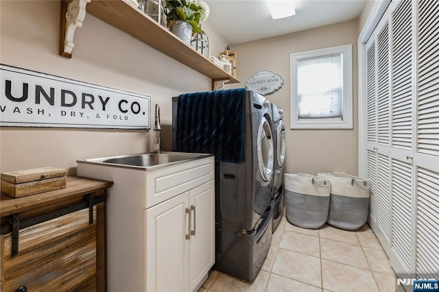 washroom with light tile patterned floors, a sink, washing machine and dryer, and cabinet space