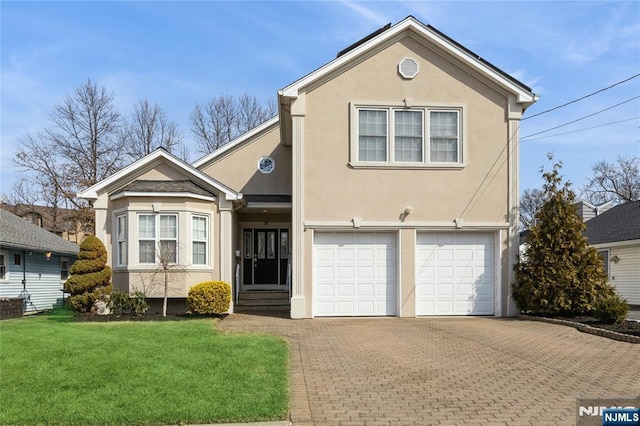 traditional-style home with decorative driveway, stucco siding, an attached garage, a front yard, and entry steps