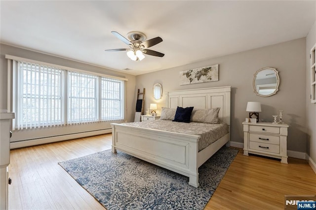 bedroom featuring ceiling fan, baseboard heating, light wood-type flooring, and baseboards