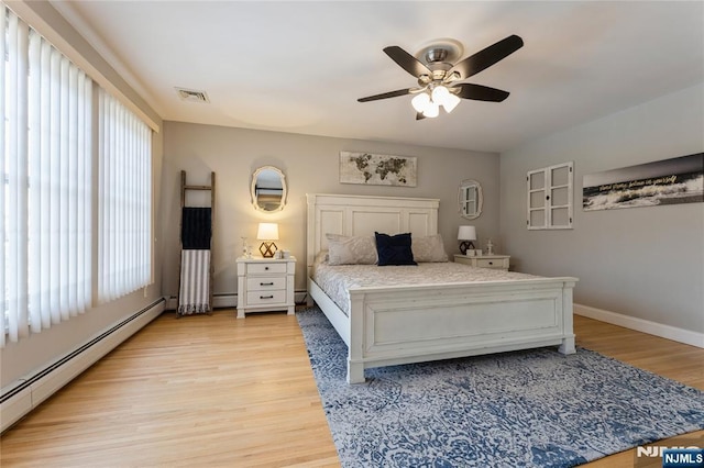 bedroom featuring light wood finished floors, a baseboard radiator, visible vents, and baseboards