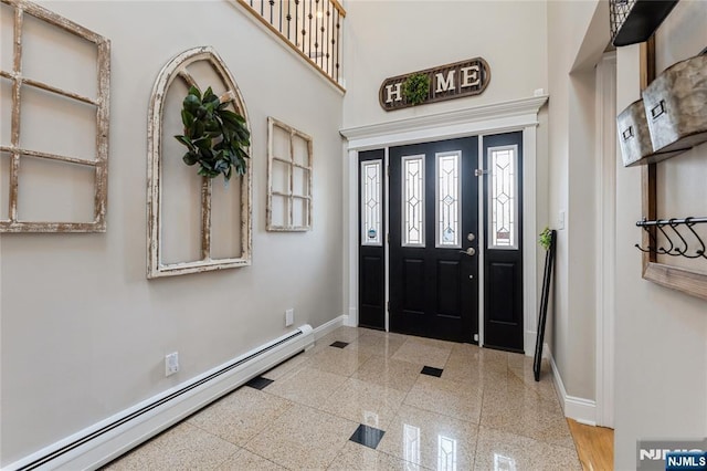 entryway with a baseboard radiator, granite finish floor, a towering ceiling, and baseboards