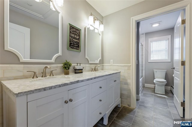 bathroom with wainscoting, a sink, tile walls, and toilet