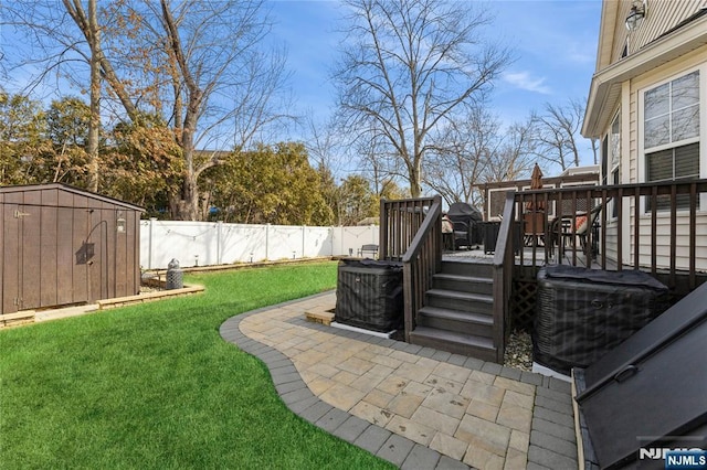 view of yard featuring an outbuilding, a patio, a deck, a fenced backyard, and a shed