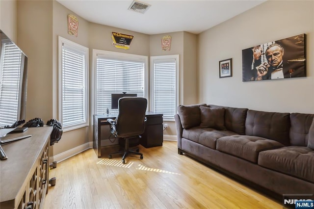 office space with light wood finished floors, plenty of natural light, visible vents, and baseboards