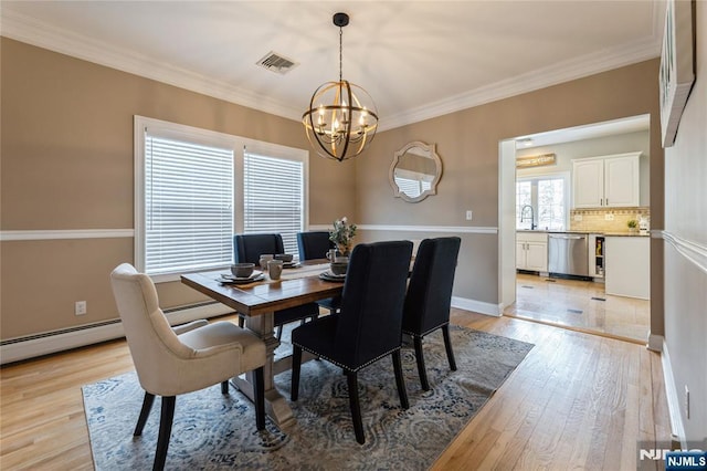 dining area featuring crown molding, a notable chandelier, light wood finished floors, visible vents, and baseboards